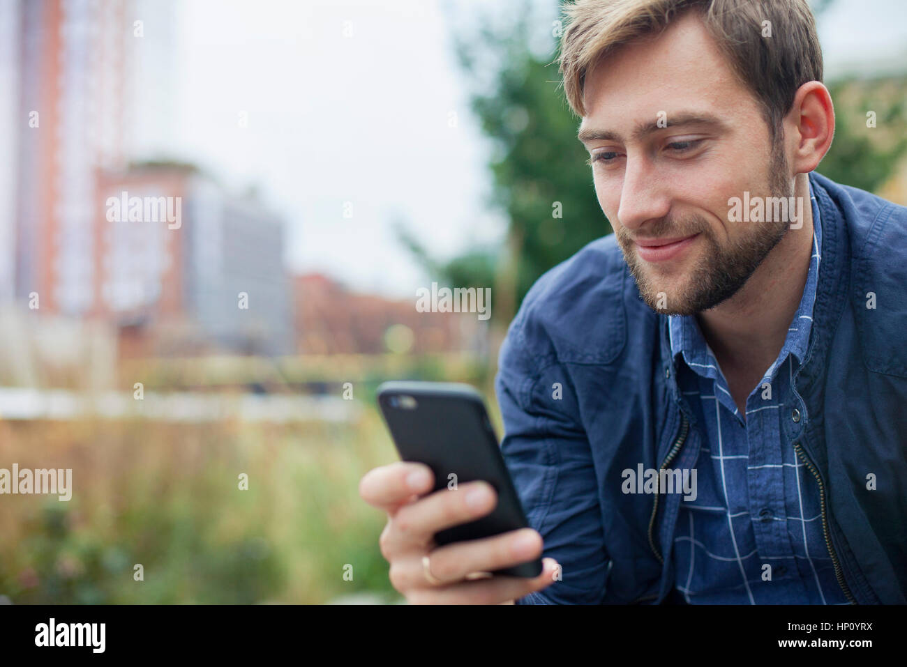 Mann im Park entspannen, mit Blick auf Multimedia-smartphone Stockfoto