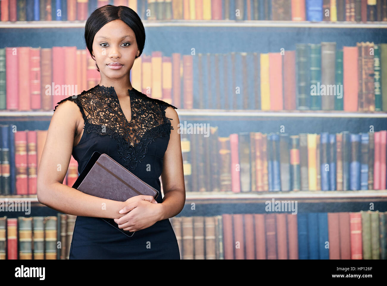Attraktive schwarze Frau stand vor Bücher halten notebook Stockfoto
