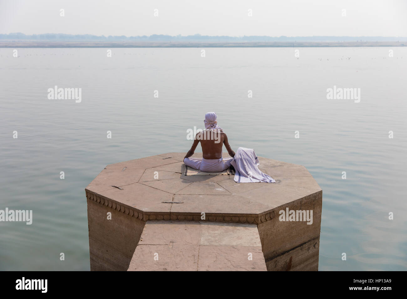 Ein Mann meditiert über den Ganges in Varanasi, eine der heiligsten Städte Indiens. Varanasi ist ein beliebtes Ziel für Touristen, die Teilnahme an Yoga-Schulen. Stockfoto