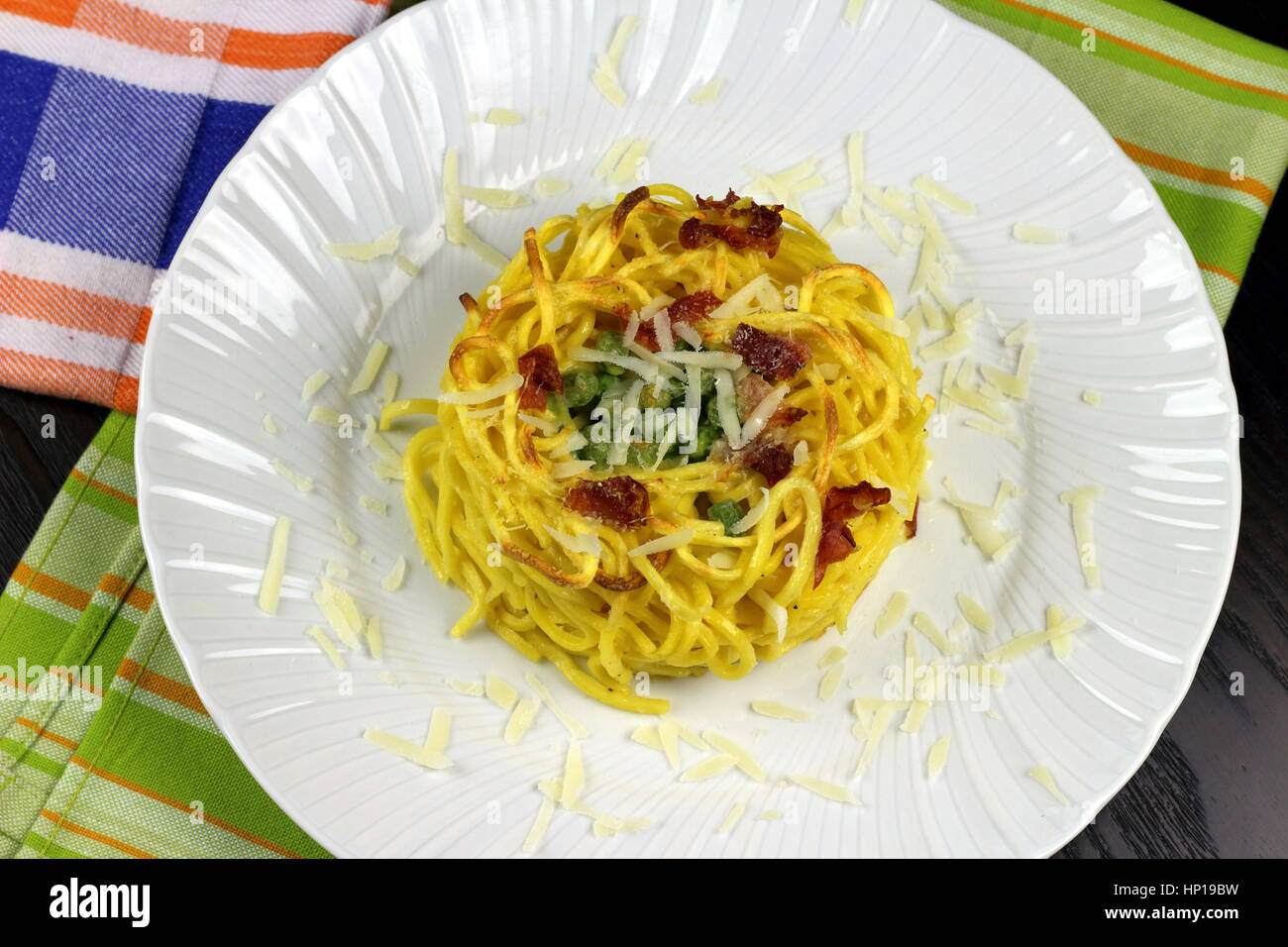 Gebackener Taleggio-Käse, Speck (auch Speck oder Kissen) und Erbsen frische Tagliolini Pasta in weißen Schale auf bunte Küchentücher - italienische Küche-Rezept Stockfoto