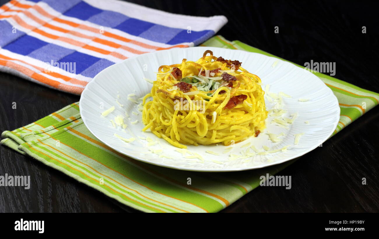 Gebackener Taleggio-Käse, Speck (auch Speck oder Kissen) und Erbsen frische Tagliolini Pasta in weißen Schale auf bunte Küchentücher - italienische Küche-Rezept Stockfoto