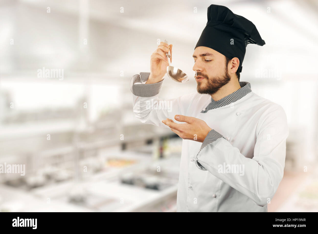 Qualitätskontrolle - Chef tasting Suppe aus Pfanne in Küche Stockfoto