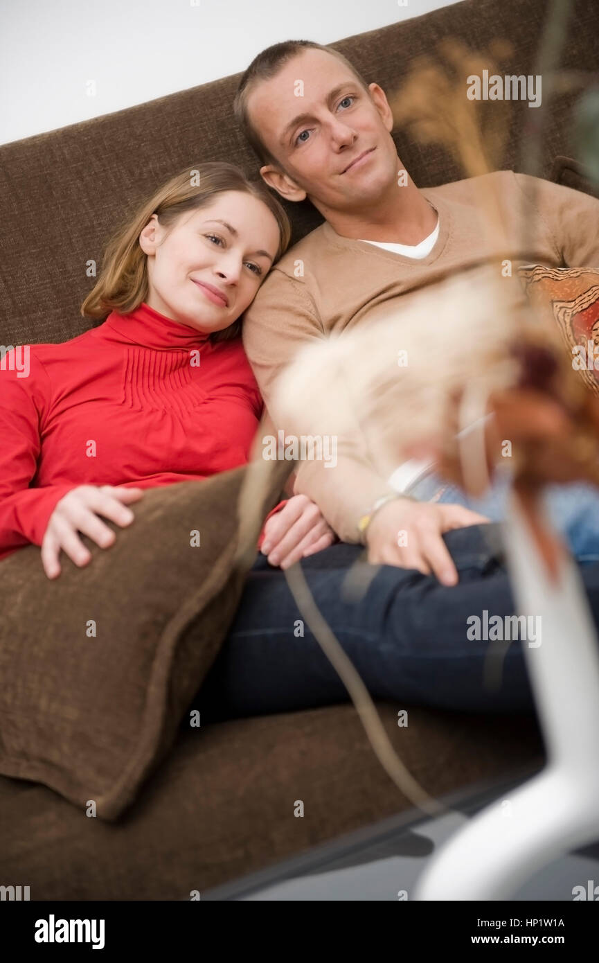 Model Release, Liebespaar Sitzt Gemeinsam Auf der Couch - Liebespaar sitzt auf einer Couch zu Hause Stockfoto