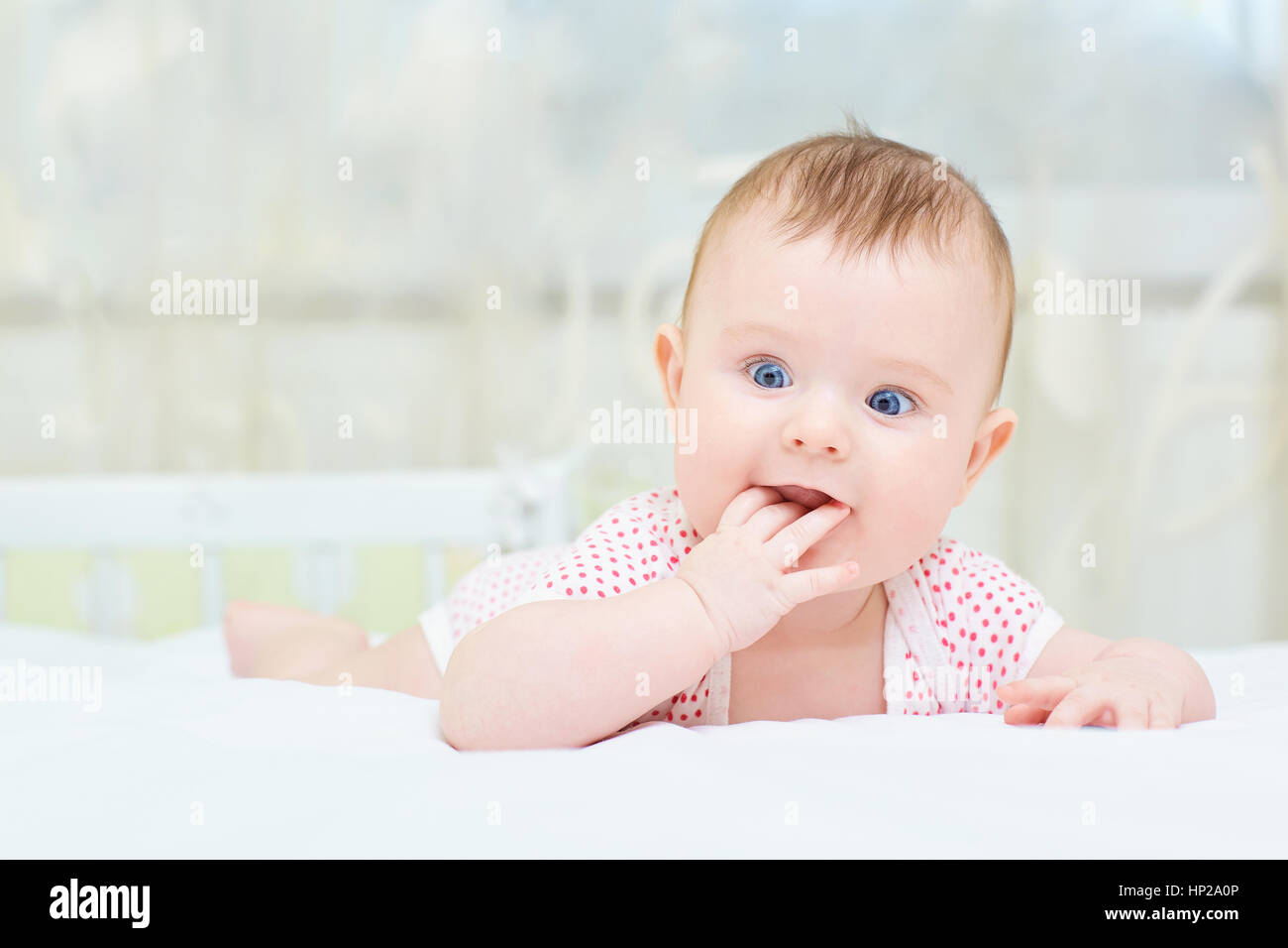 Lustige Baby Kleinkind Kind mit blauen Augen auf dem Bett liegend Stockfoto
