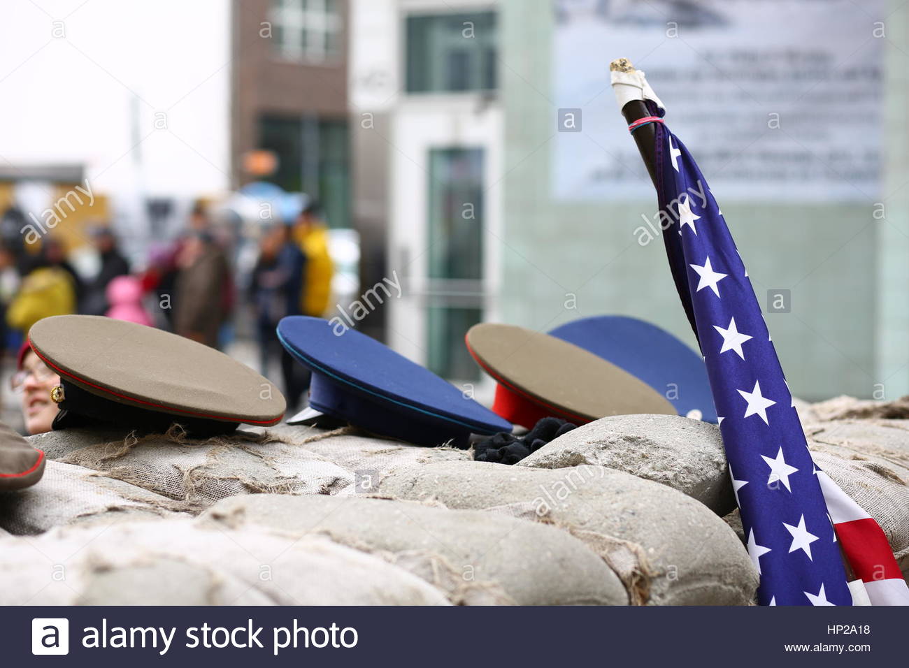 Eine US-Flagge und militärische Hüte aus der Zeit des Kalten Krieges am Checkpoint Charlie in Berlin. Stockfoto
