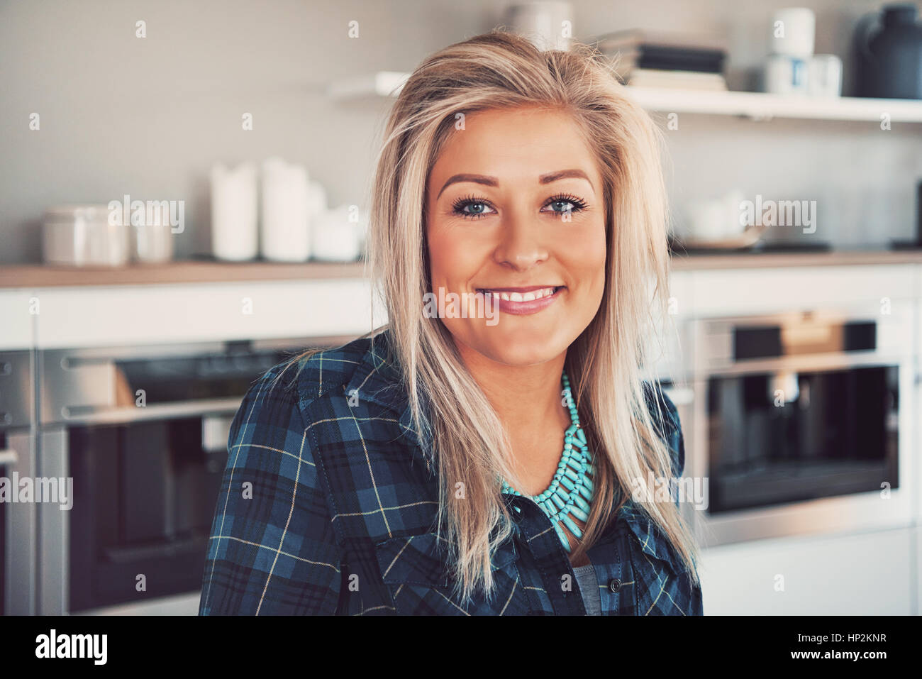 Niedlichen blonden Frau in blau Flanellhemd vor Mikrowellen im Restaurantküche Stockfoto