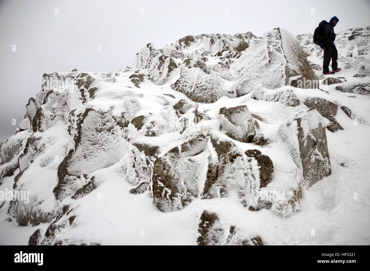 Einsame männliche Walker Klettern in einem Schnee Schneesturm, Wainwright Esk Pike von Esk Hause im Lake District National Park, Cumbria, UK. Stockfoto