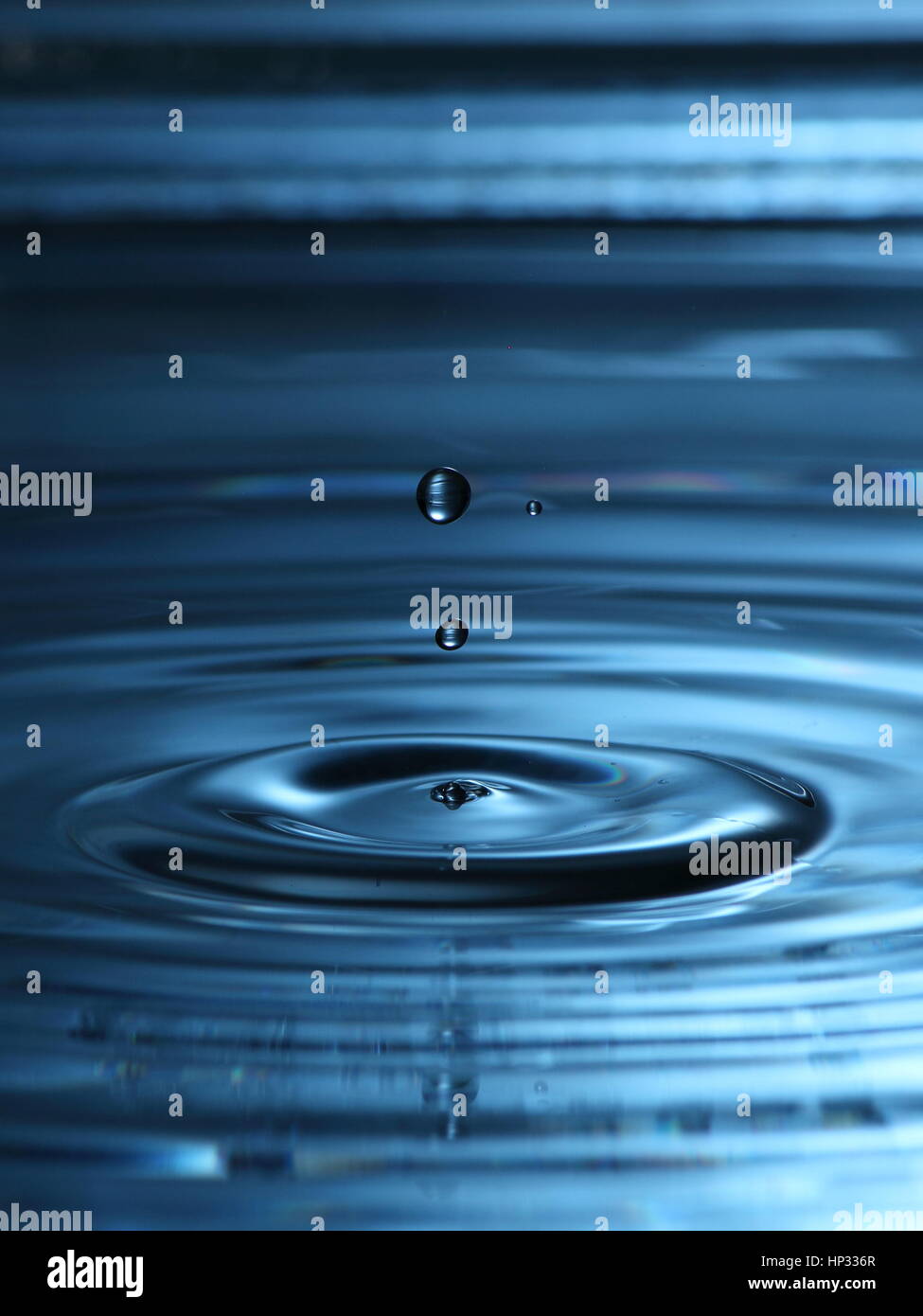 Schwebenden Planeten: Wasser Tropfen Fotografie, mit eine große Welle und schwimmende Tropfen über die Oberfläche und blaue Reflexion Stockfoto