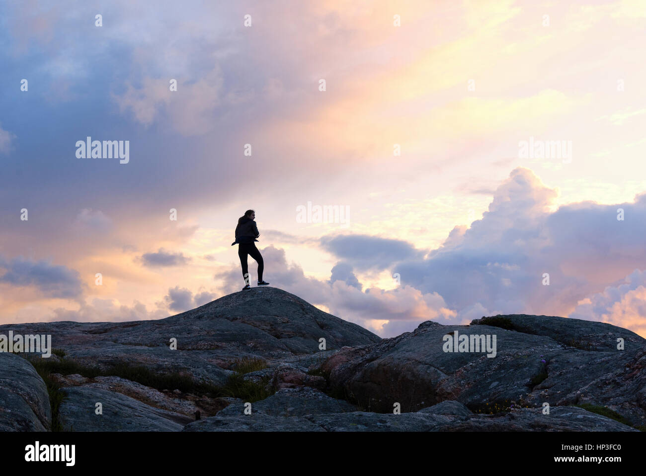 Eine starke weibliche auf de stehen Felsen nahe des Leuchtturms von Lindesnes - Norwegen - während des Sonnenuntergangs. Stockfoto