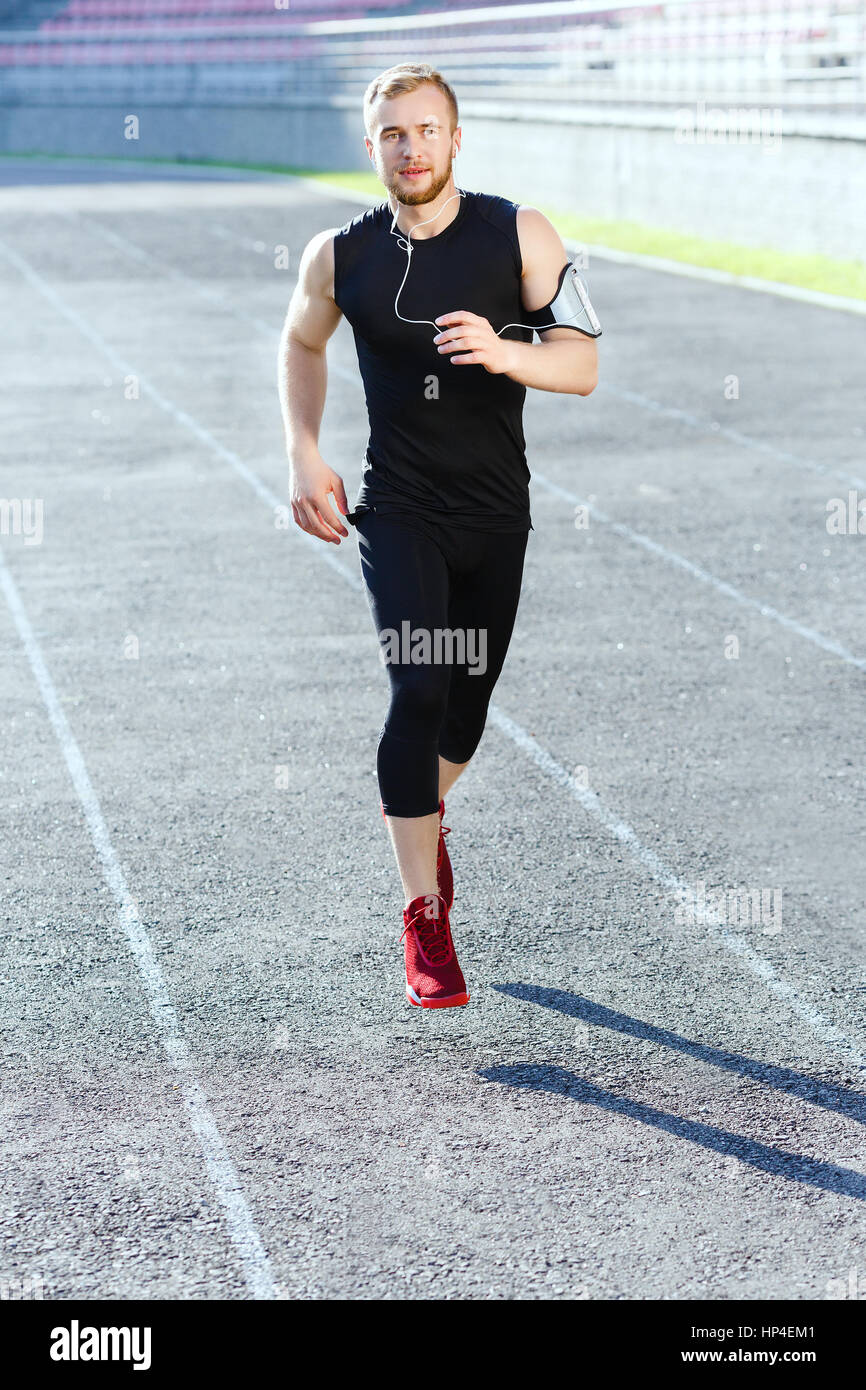 Mann im schwarzen Trainingsanzug läuft auf Strecke Stockfoto