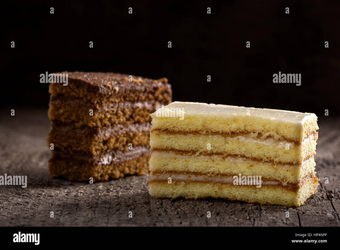 Zwei Stück Kuchen, eine mit Kakao Creme und das andere mit Vanille und Käse Creme auf hölzernen Hintergrund Stockfoto