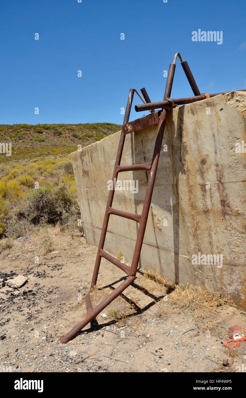 Gebrochen, rostigen Metall-Leiter an einer Betonwand Stockfoto