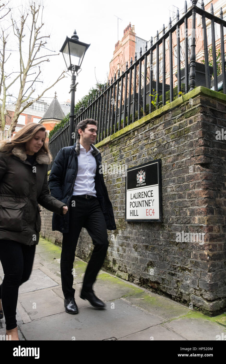 Ein junger Mann und eine junge Frau, die den Laurence Pountney Hill in London, England, Großbritannien, hinunterlaufen Stockfoto