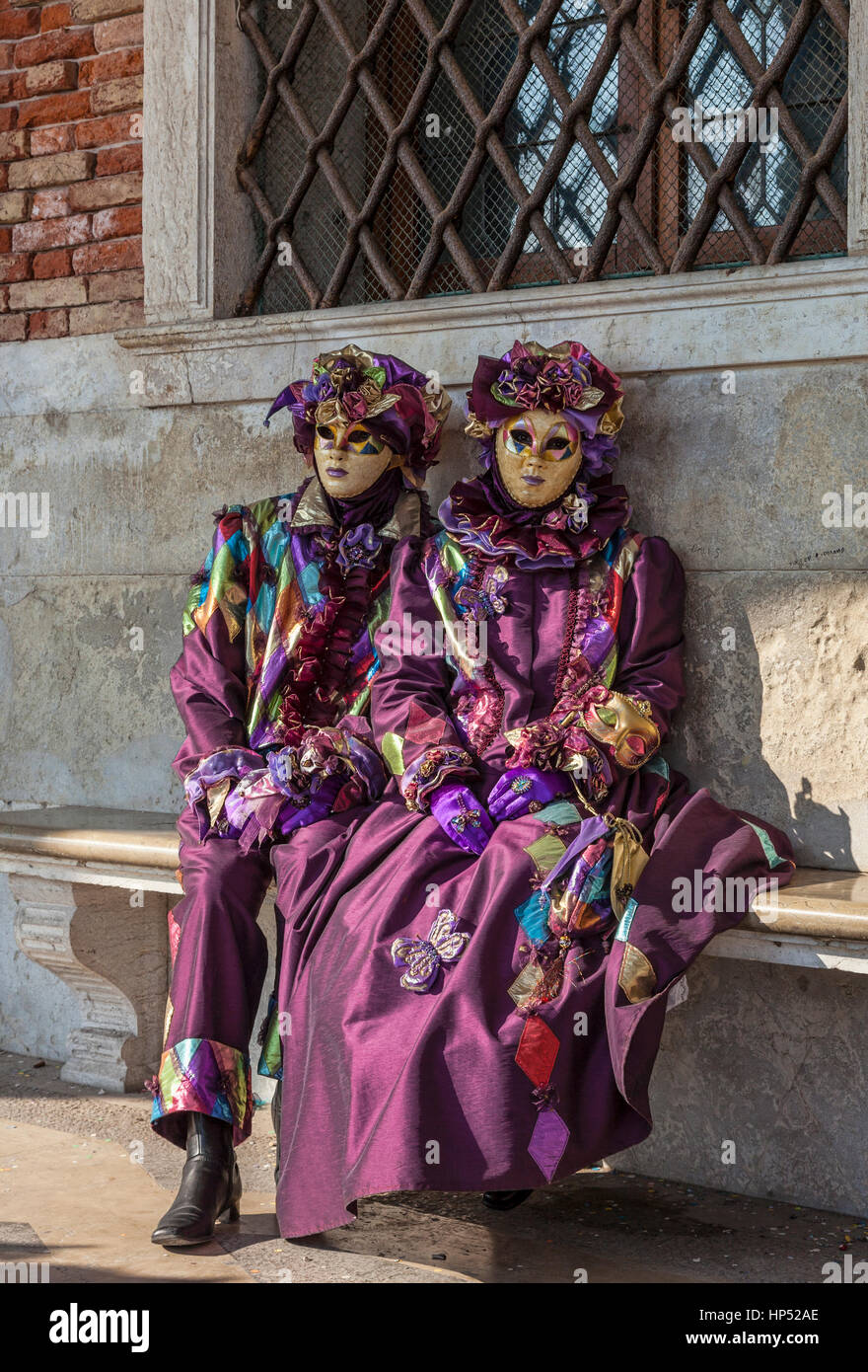 Venedig, Italien - 18. Februar 2012: zwei Menschen verkleidet in lila Kostüme venezianische sitzen auf einer Bank in den Karneval von Venedig-Tagen. Stockfoto