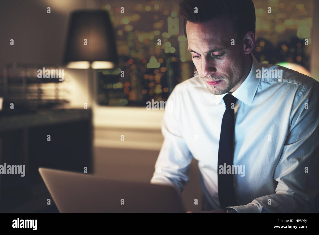 Geschäftsmann, arbeiten am Laptop nachts sitzen im Büro, große Stadt im Hintergrund, Überstunden-Konzept Stockfoto