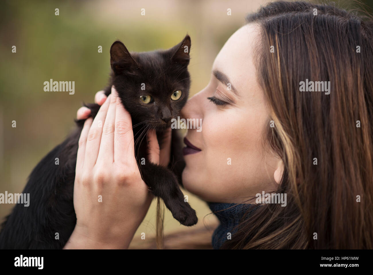 Junge hübsche Frau Kuscheln mit einer schwarzen Katze Stockfoto