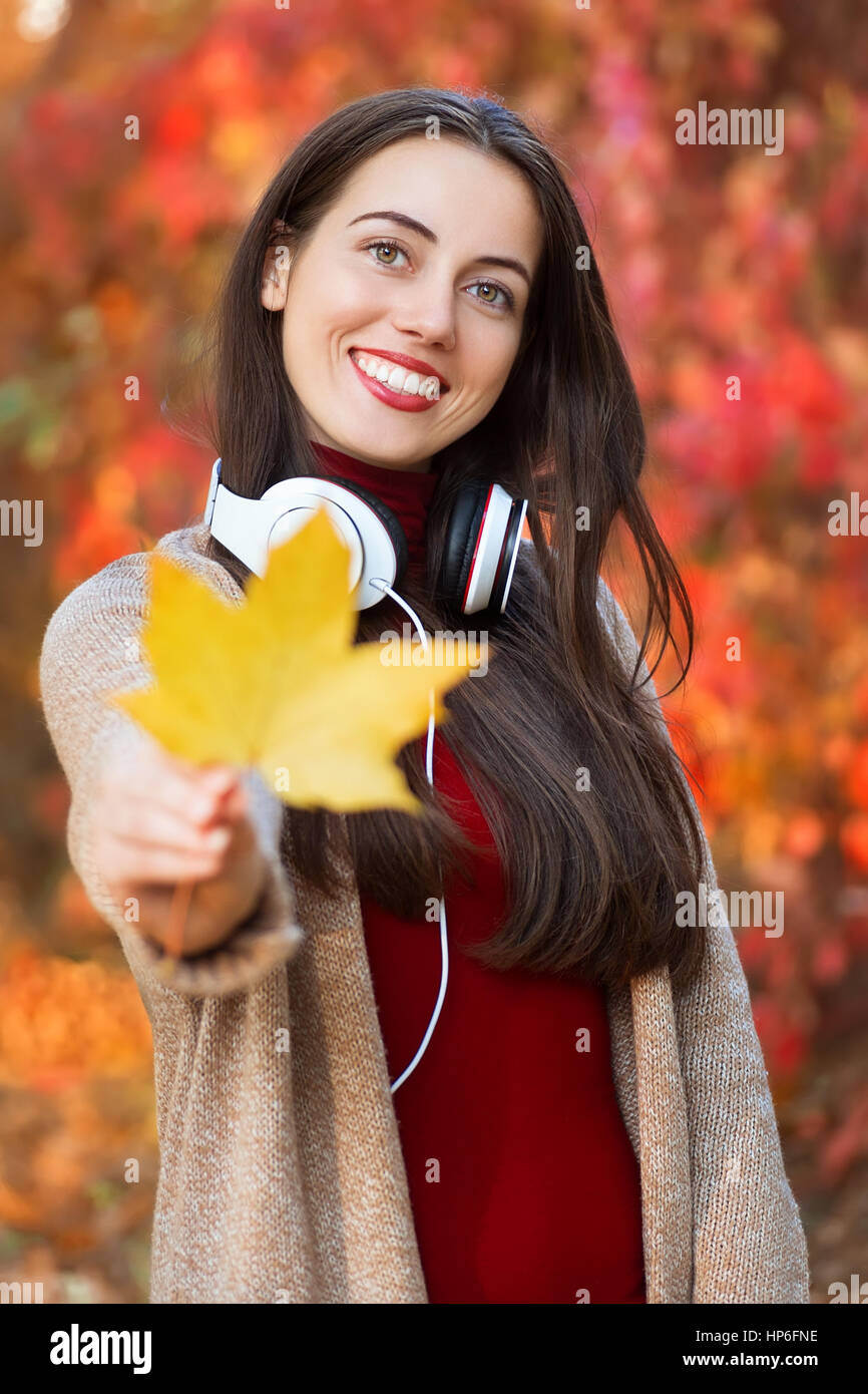 Mädchen halten Herbst orange Ahornblatt. Schöne junge Brünette Frau mit Ahorn Lleaf in ihren Händen, verbringen Zeit im Herbst Park. Lächelndes Mädchen Stockfoto
