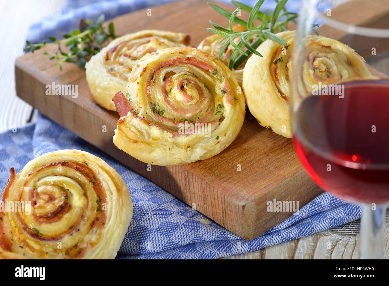 Gebackene herzhafte Blätterteig Brötchen mit Schinken, Frischkäse, Parmesan und Kräutern; serviert mit einem Glas Rotwein Stockfoto