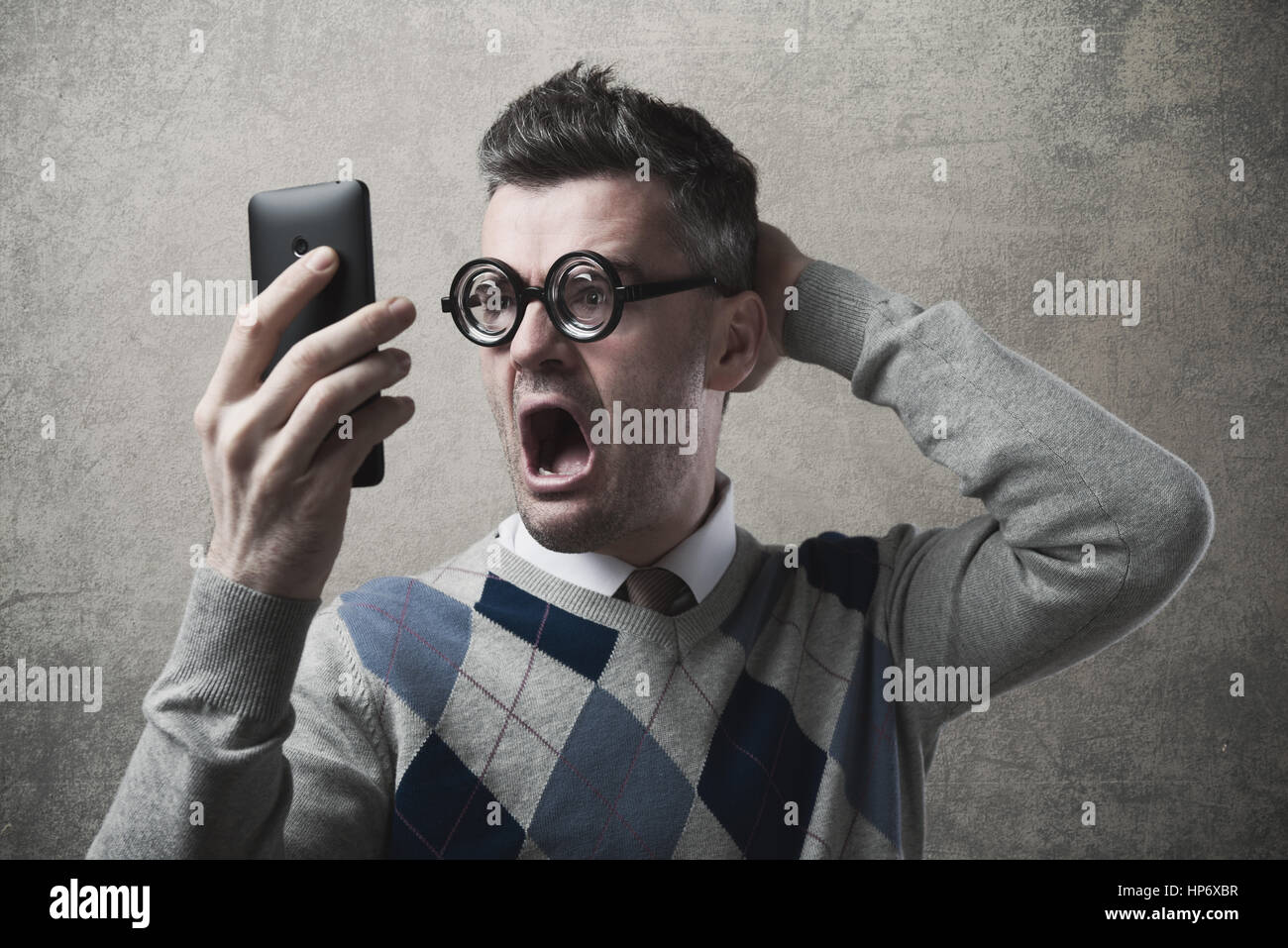 Lustig erstaunt zorniger Mann Probleme mit seinem smartphone Stockfoto