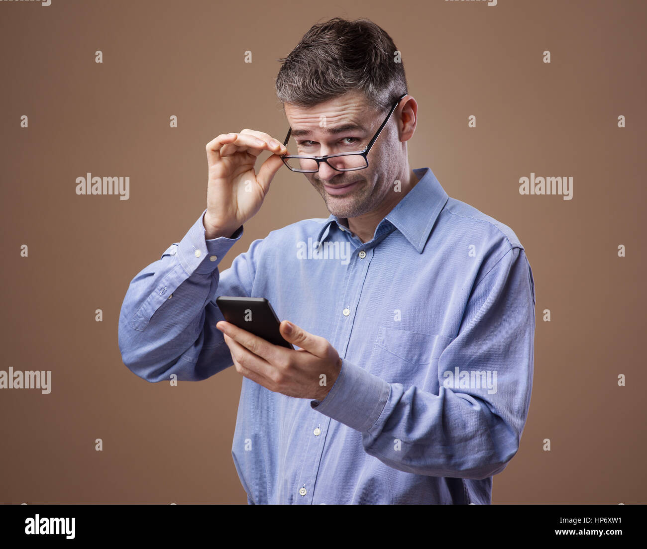Geschäftsmann, seine Brille beim Lesen von Nachrichten auf seinem Smartphone einstellen Stockfoto