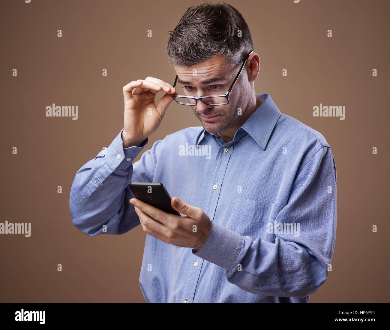 Geschäftsmann, seine Brille beim Lesen von Nachrichten auf seinem Smartphone einstellen Stockfoto