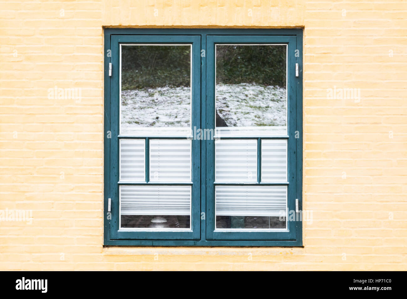Gelben Ziegelwand mit alten Fenster im grünen Holzrahmen und geschlossenen Lamellen, Hintergrundtextur Stockfoto