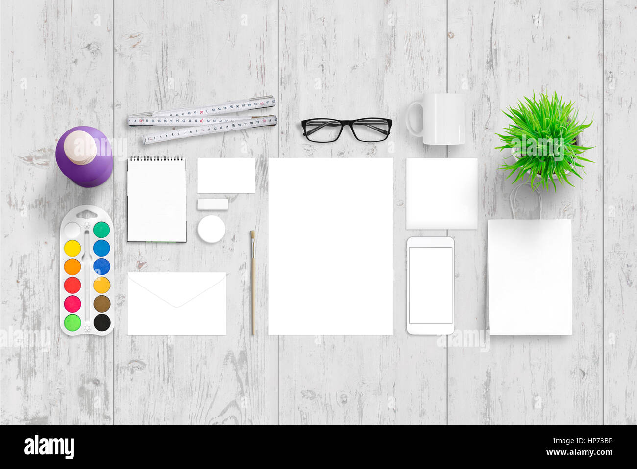 Büromaterial für corporate branding. Draufsicht der weißen Schreibtisch aus Holz mit Papier, Pad, Tasche, Briefumschlag, Visitenkarte, Abzeichen, Becher, Pflanze, Brille, wat Stockfoto