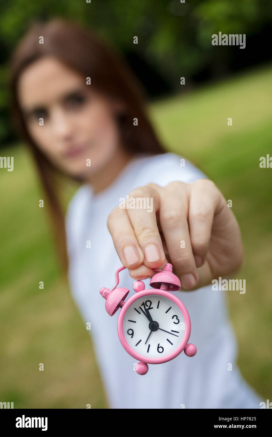 Junge Frau oder Mädchen außerhalb hält einen rosa Wecker rechtzeitig zur Neige Konzept Foto Stockfoto