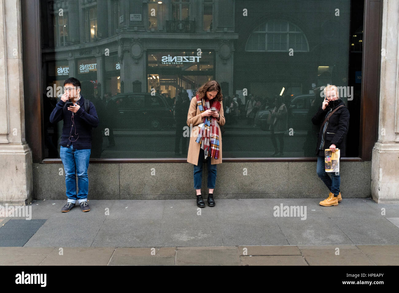 Drei junge Leute, die Verwendung von Mobiltelefonen in der Straße Stockfoto