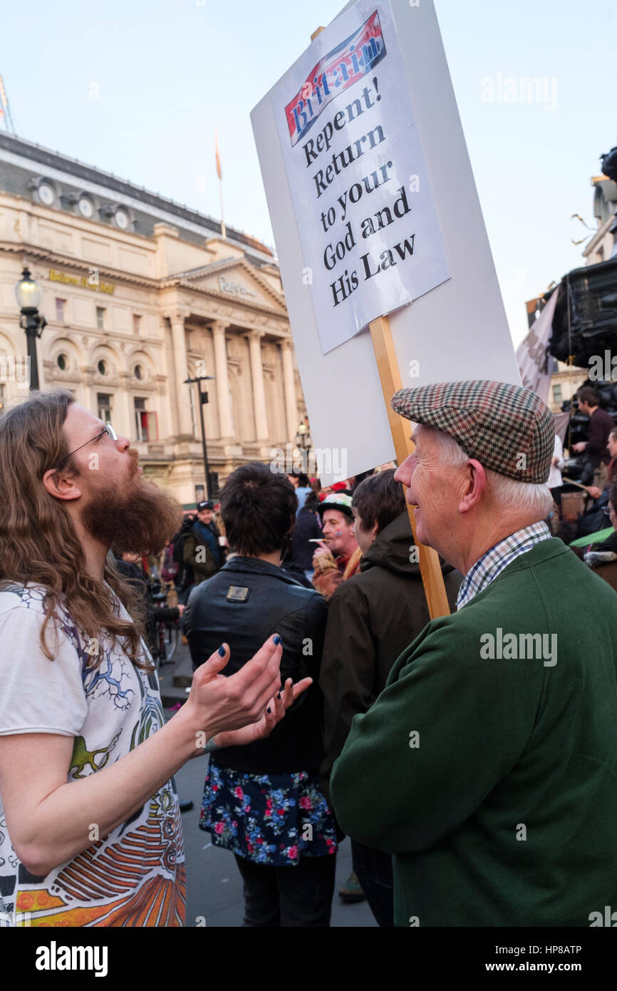 Christlicher Evangelist tragen religiöse Plakat unterhält sich mit junger Mann, London, UK Stockfoto