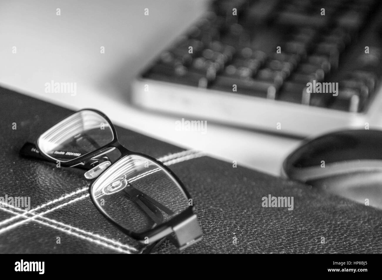Brille in der Nähe einer Computer-Tastatur und Maus platziert Stockfoto