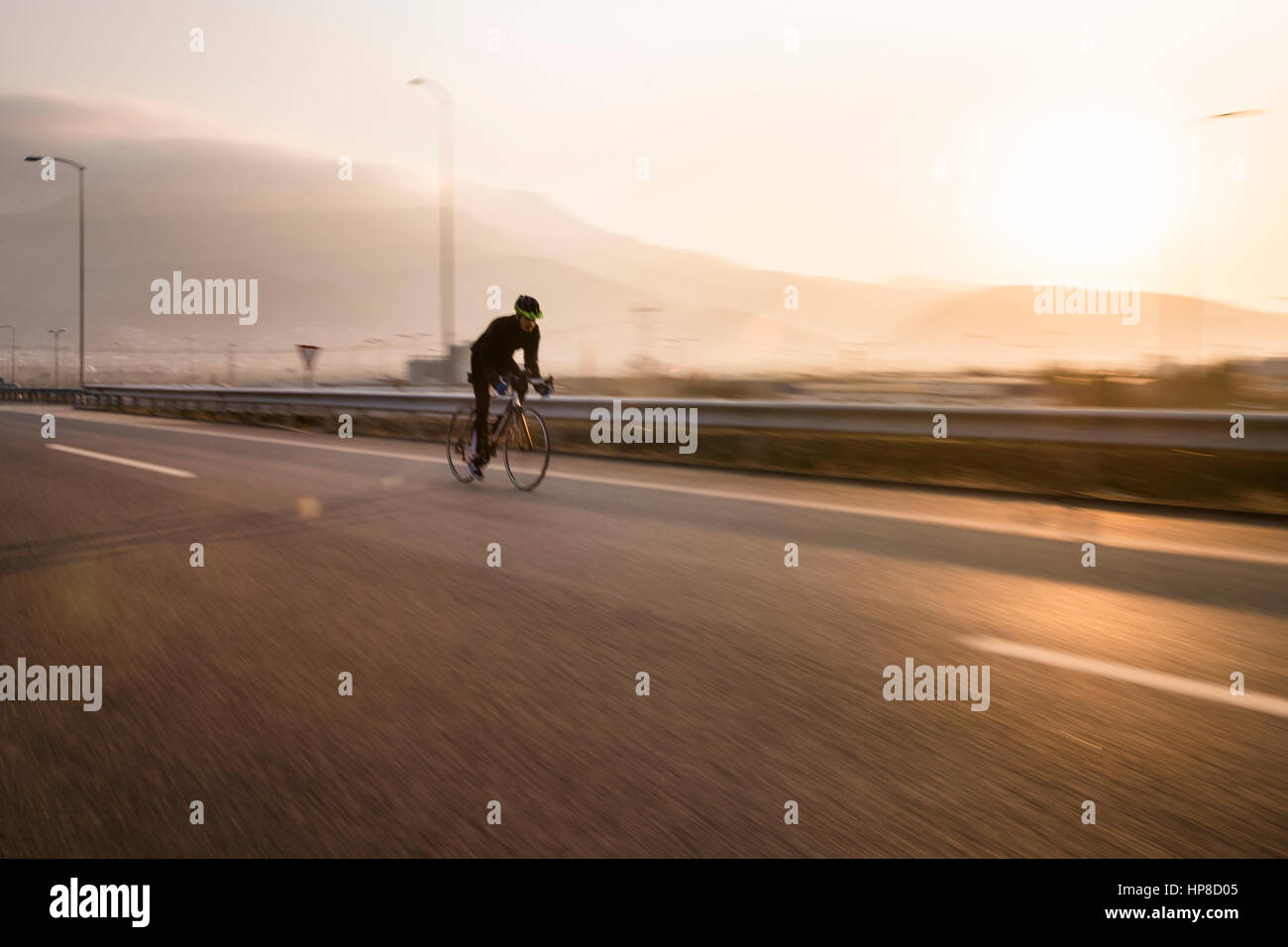 Schnelle Radfahrer auf Autobahn und Sonnenuntergang mit Bewegungsunschärfe. Stockfoto