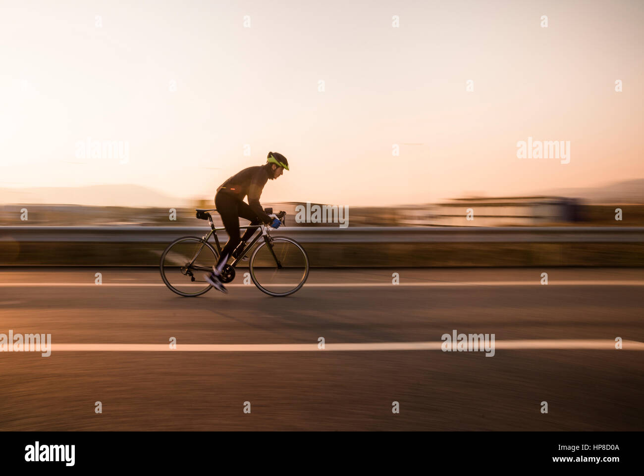 Schnelle Radfahrer auf Autobahn und Sonnenuntergang mit Bewegungsunschärfe. Stockfoto
