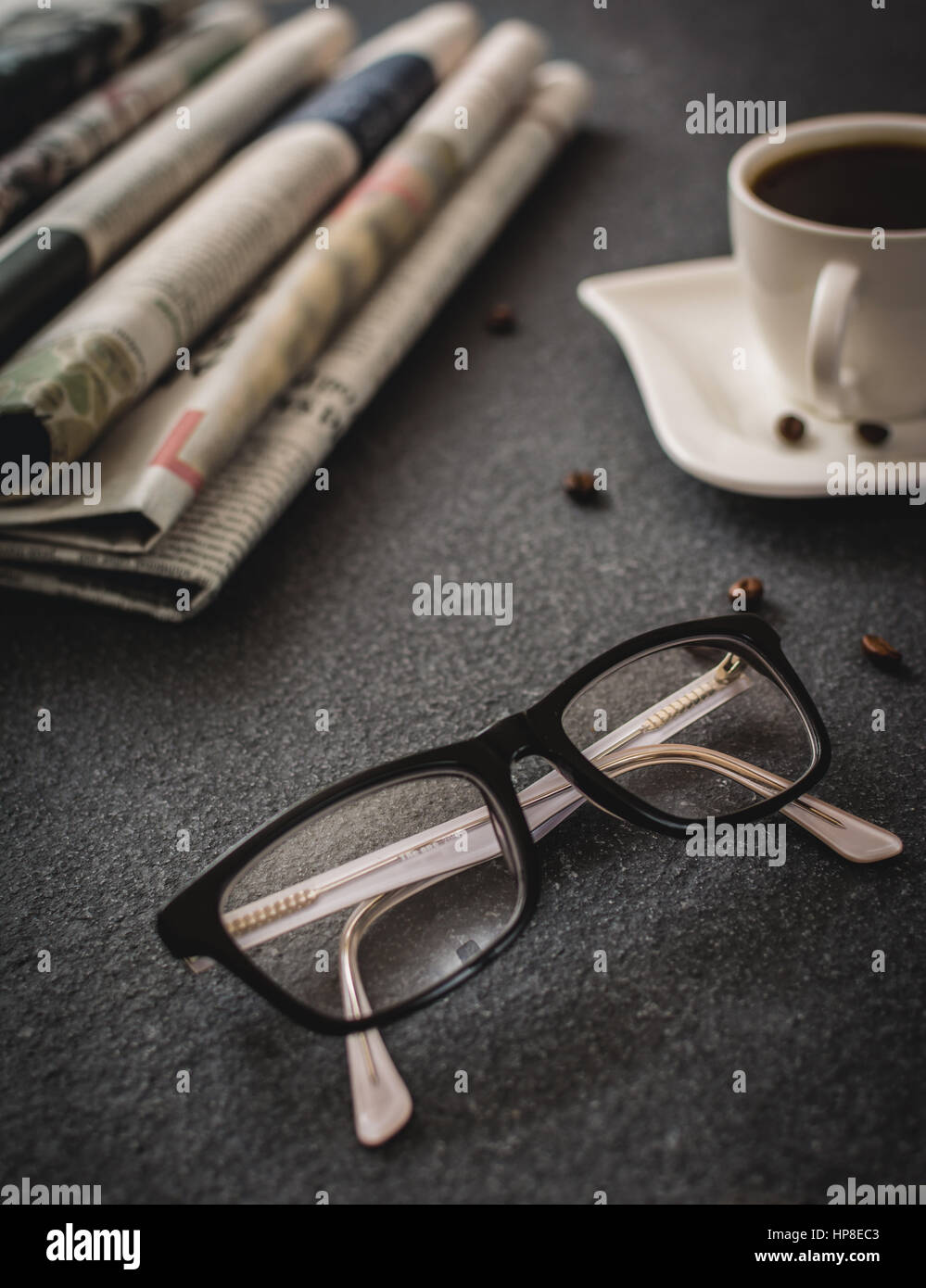 Klassen und Zeitung und Kaffee auf schwarzem Stein Stockfoto