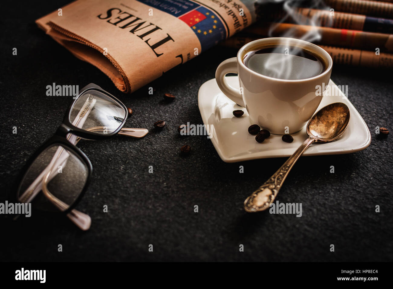 Klassen und Zeitung und Kaffee auf schwarzem Stein Stockfoto