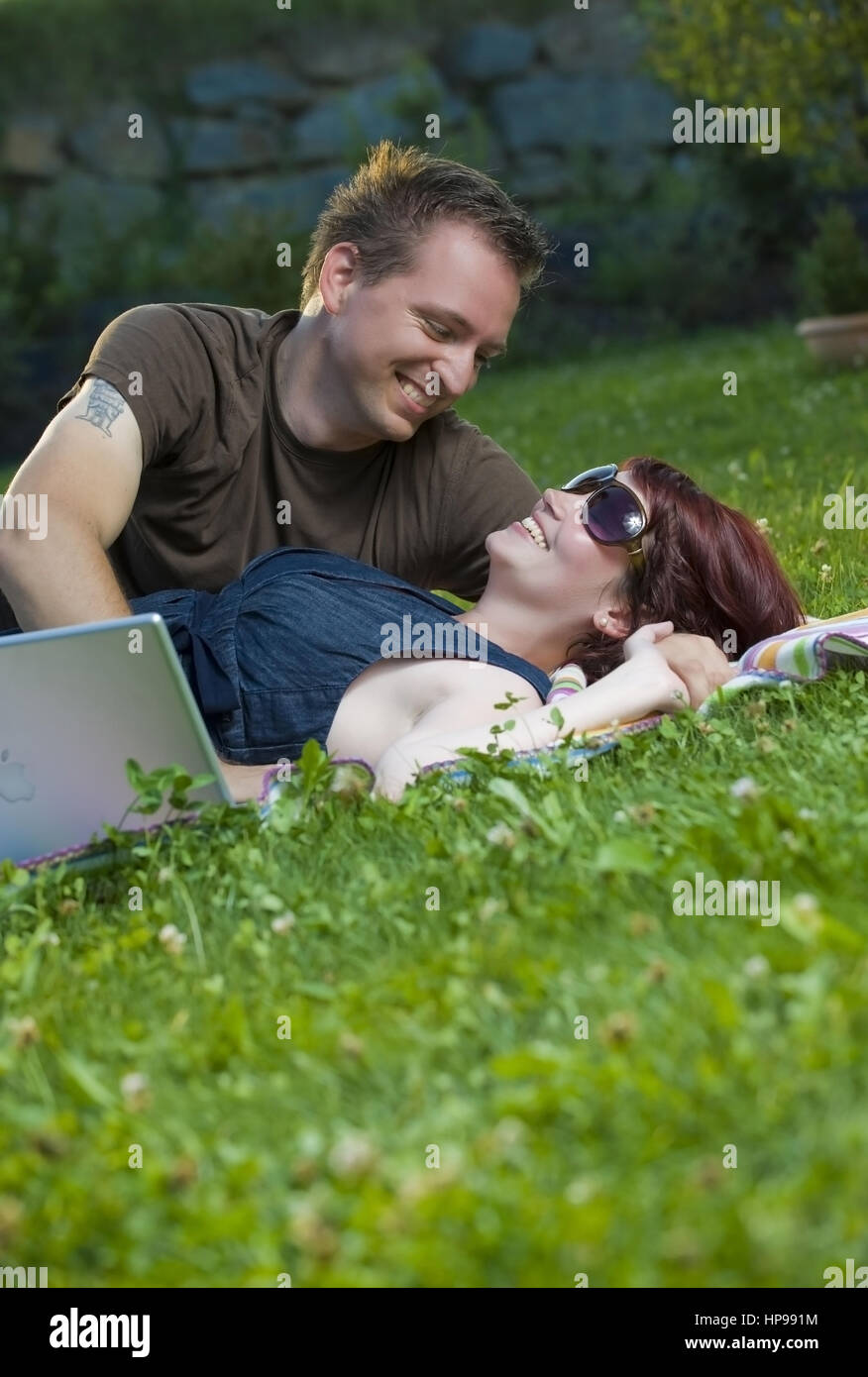 Model Release, Junges Paar so Mit Laptop Auf Einer Decke in der Wiese - paar mit Laptop in der Wiese liegend Stockfoto