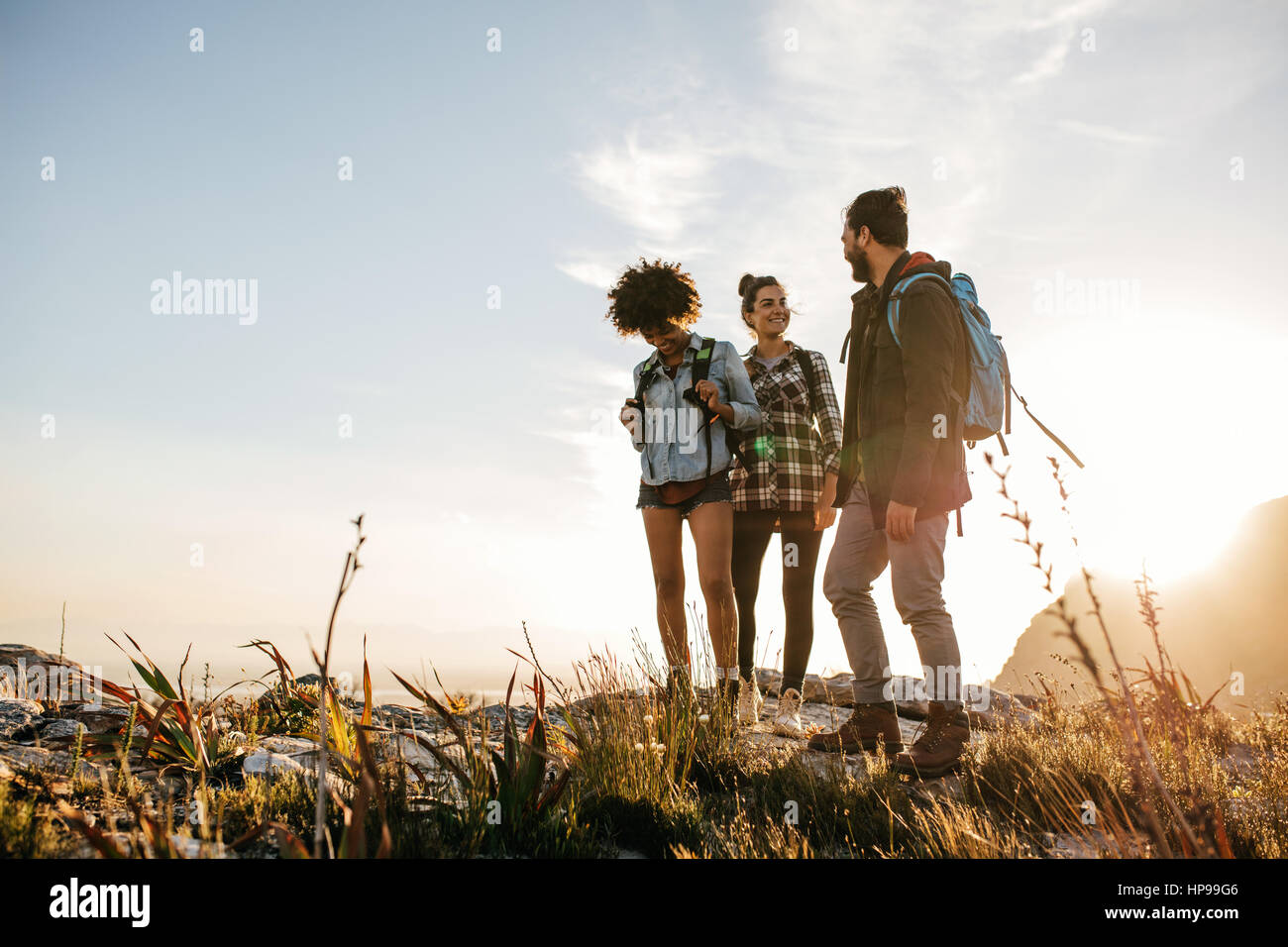 Gruppe von Personen, die an einem Sommertag in der Natur wandern. Drei junge Freunde auf ein Land gehen. Stockfoto