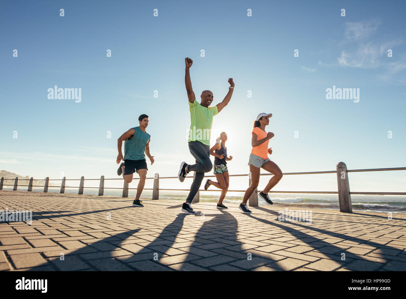 Voller Länge Schuss von jungen Menschen, die entlang am Meer mit jungen Mann das Rennen zu gewinnen. Stockfoto