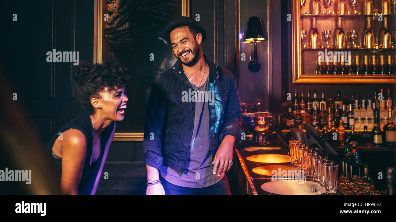 Glückliches Paar bei Lounge-Disco-Bar-Theke und lachen. Junge Leute, die Spaß in einem Club. Stockfoto