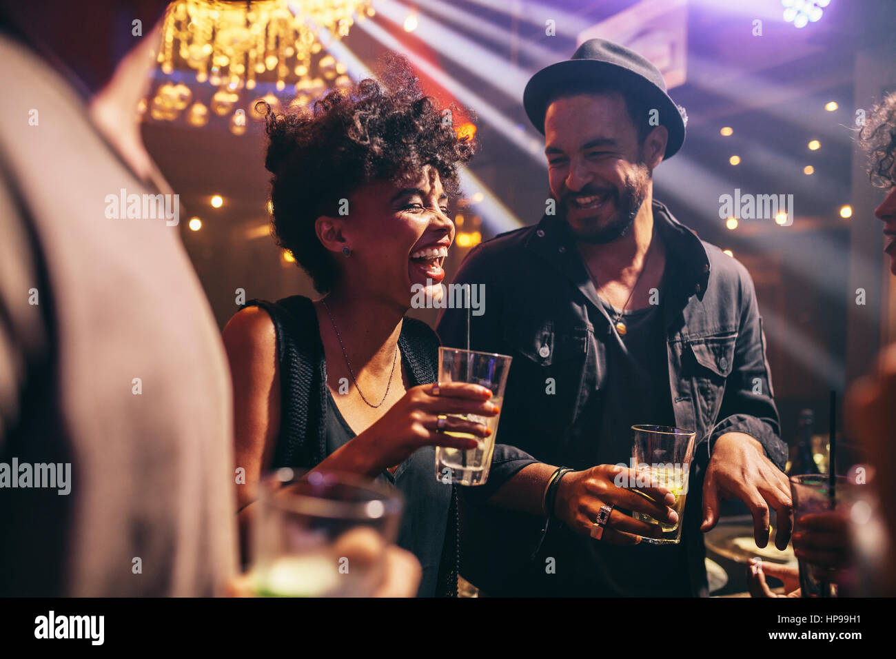 Gruppe junger Freunde an einem Abend im Pub. Glückliche junge Männer und Frauen, die Getränke und lächelnd im Night Club. Stockfoto