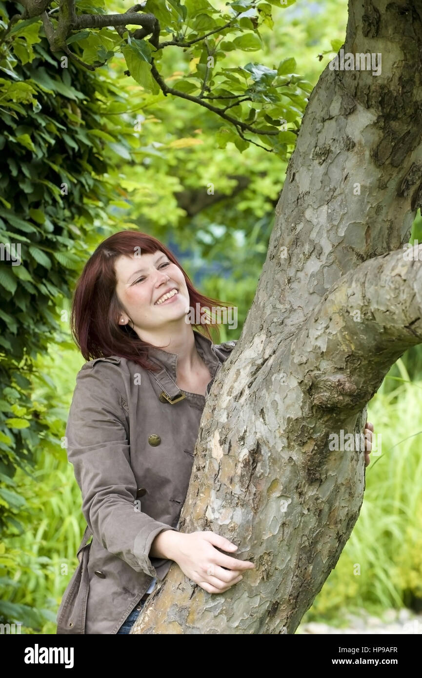 Model Release, Froehliche Frau, 25 +, Umgreift Einen Baumstamm - glückliche Frau neben einem Baum Stockfoto