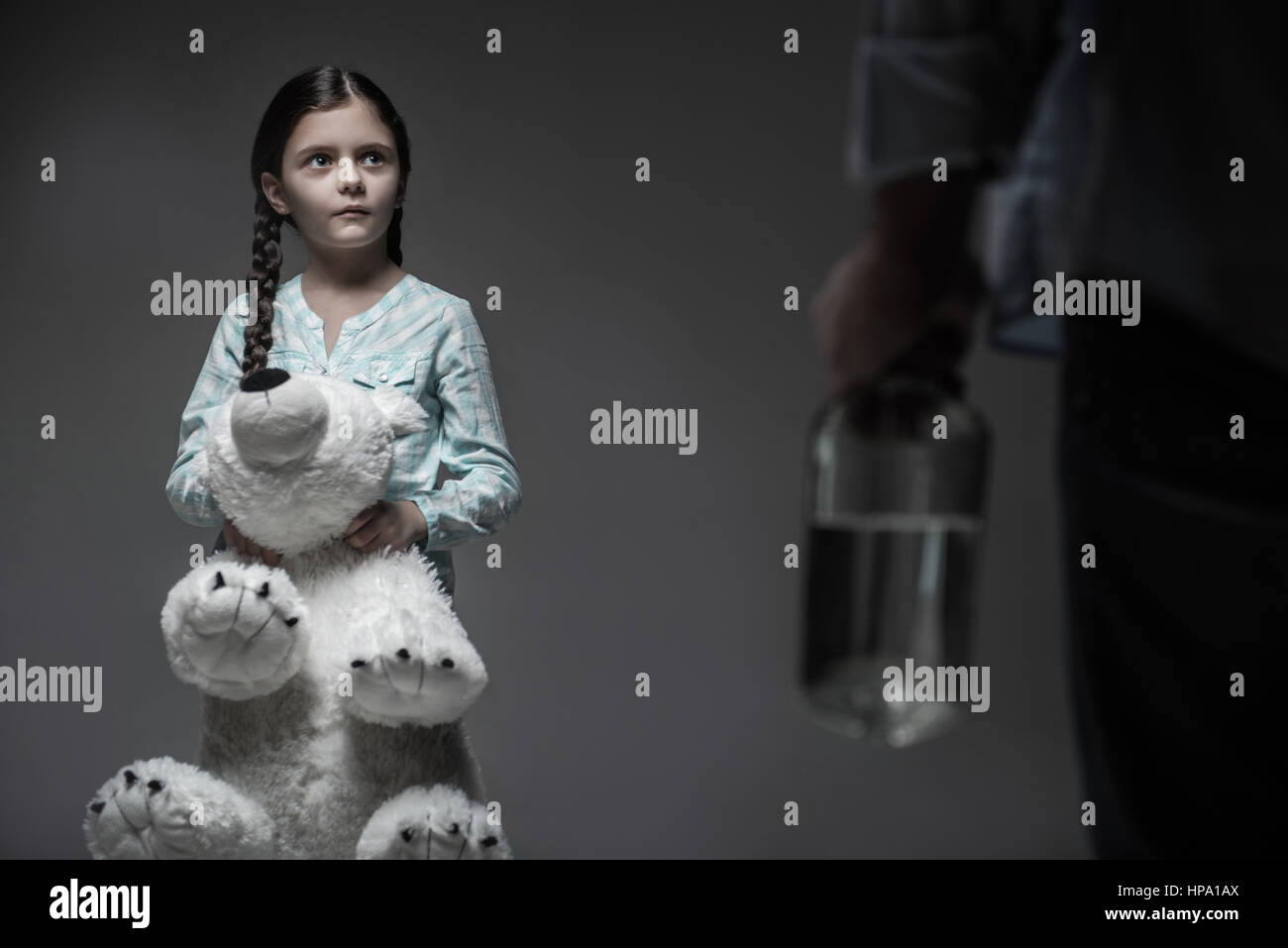 Familie Kummer. Verängstigten Mädchen drücken ihre Lippen, während männliche Person mit Flasche in der hand, betrachten mit großer weißer Bär Stockfoto