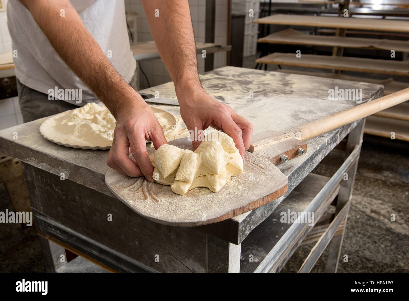 Köche Hände close-up geben Form zu Teig zum Backen von Brot, über hölzernen Schale in Bäckerei Stockfoto
