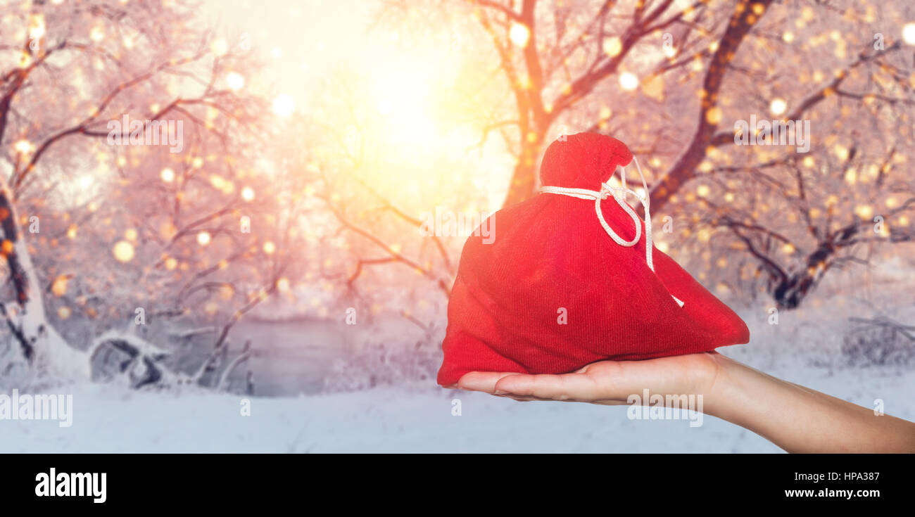 Urlaub Verkauf Hintergrund. Roter Sack in der Hand auf Winter Hintergrund. Rote Tasche mit Geschenken zu Weihnachten Hintergrund. Stockfoto