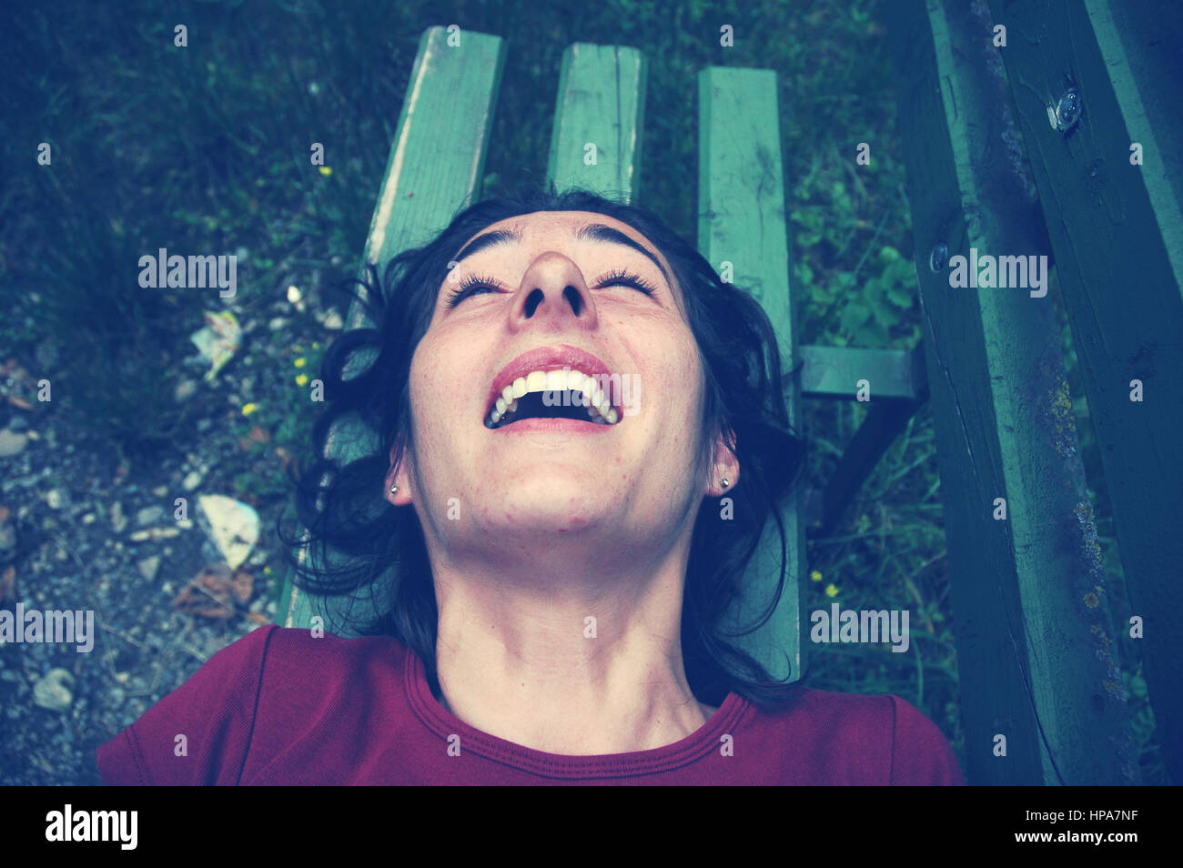 Kitzeln, kitzelte Frau lachend auf einer Bank. Getönten Bild Stockfoto