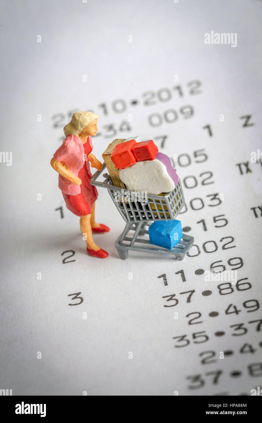 Miniatur-Figur einer Frau mit einem Einkaufswagen auf einem Bon - Rechnungen / shopping Konzept Stockfoto