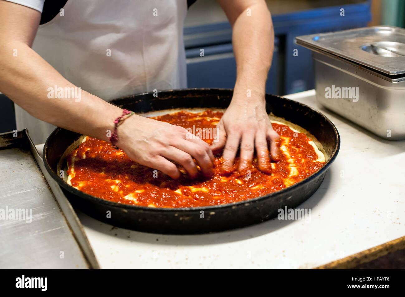 Nahaufnahme der männlichen Chef Hände arrangieren Zutaten auf der Pizza vor dem Backen in tiefe runde Pfanne Stockfoto