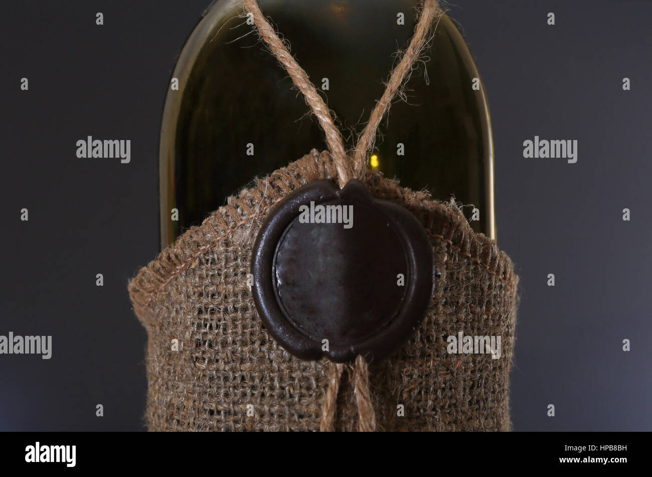 Weinflasche mit alten Siegellack Stempel Closeup. Weinflasche mit Sackleinen auf schwarzem Hintergrund gewickelt. Schöne Weingut Hintergrund. Stockfoto
