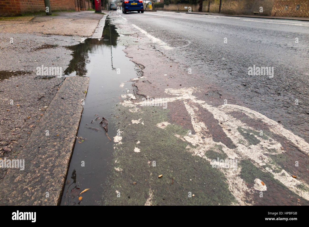 Schlechte Qualität gebrochen Fahrrad / bike / Fahrrad Lane / Bahnen mit einem geknackt / scheiternde Oberfläche & Topf Loch / Löcher / Pfütze / Pfützen. Ashford. Middlesex UK Stockfoto