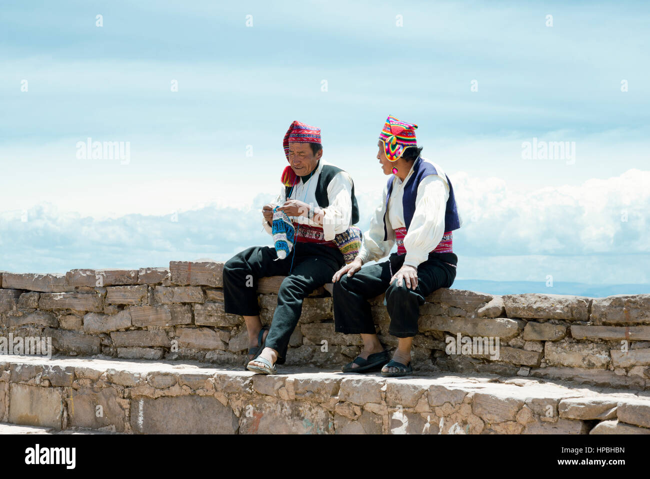 Zwei Männer gekleidet in traditionellen Outfits, die spezifisch für die Insel Taquile-Region, einer von ihnen eine Mütze stricken. Titicacasee, Peru - 17. Oktober 2012 Stockfoto